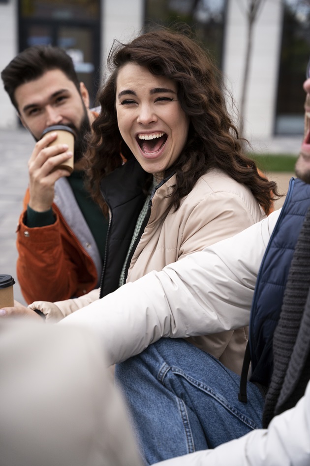 un grup de prieteni care zâmbesc și râd, la o cafea