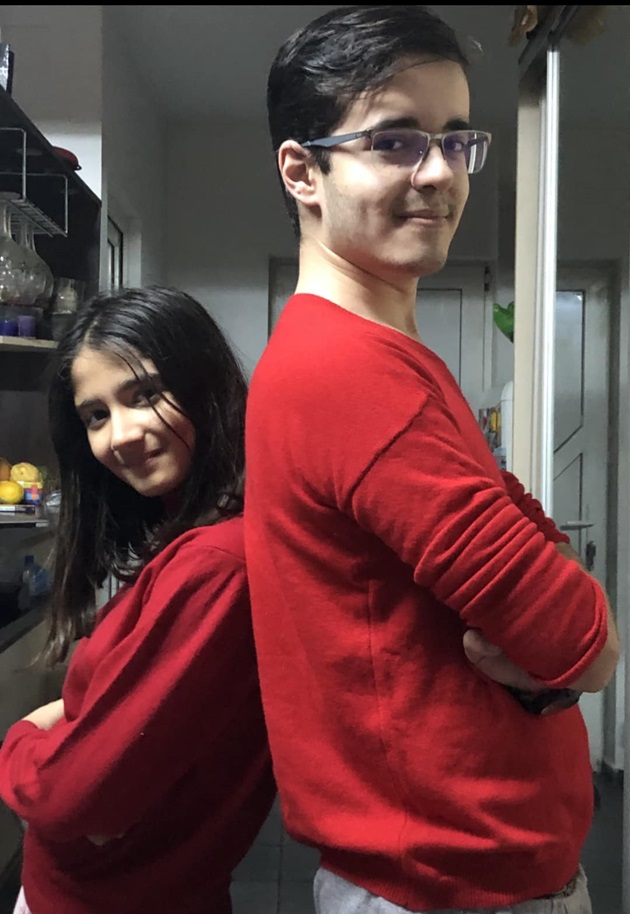 Copiii lui Daniel Iordăchioaie, Darius și Salma Nicole, stând spate în spate și purtând pulovere roșii