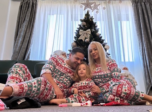 Poză de familie cu Augustin Viziru, partenera sa și fiica lor, micuța Maria, stând în fața bradului de crăciun, îmbrăcați în pijamale matchy