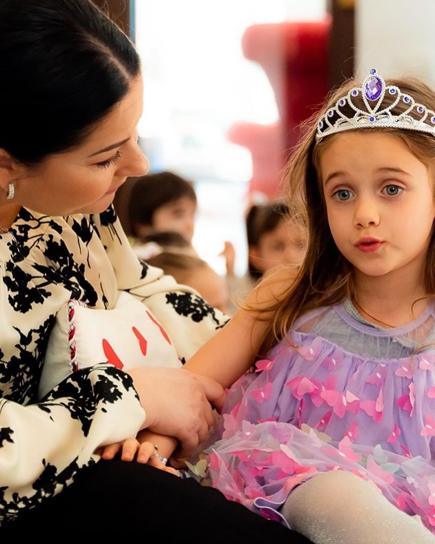 Gabriela Cristea care vorbește si o mângâie pe micuța Iris, îmbrăcată în prințesă, la ziua ei de naștere
