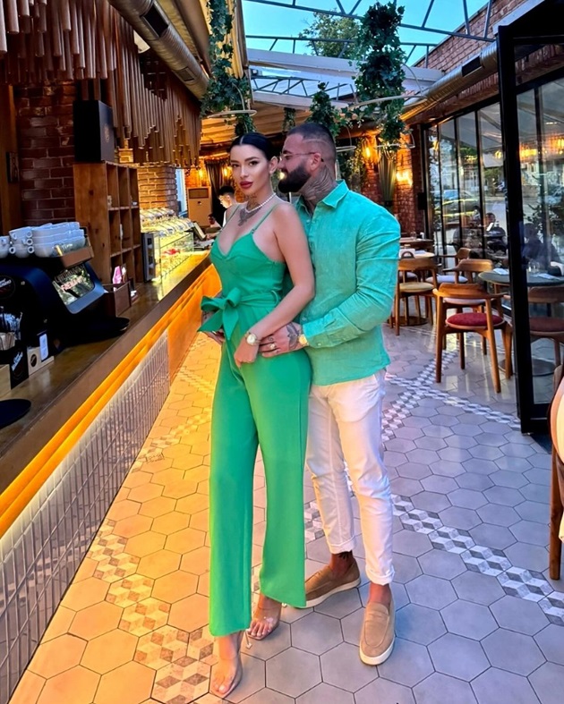 Marcel de la Insula Iubirii, alături de iubita lui, stând in picioare, îmbrățișați, si purtând o ținută matchy de culoare verde
