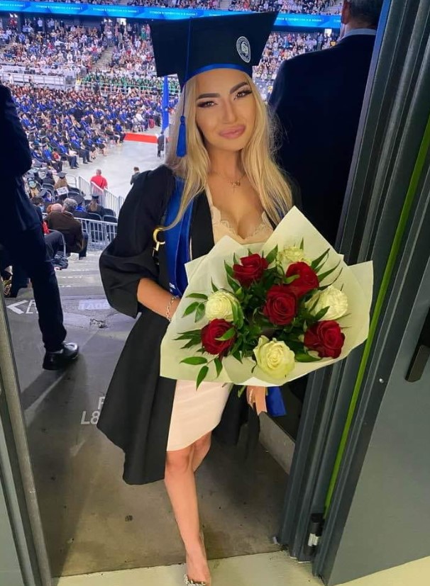 Maria Tibleș blondă, ținând un buchet mare de flori, in mână, la absolvirea facultății