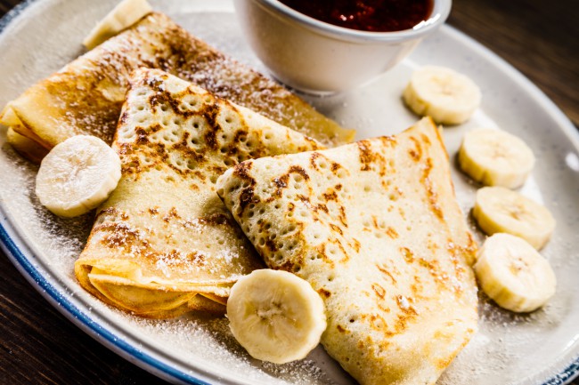 crepes cu banane alaturi de un vas cu topping