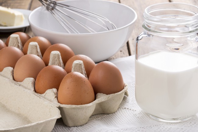 lapte, unt si oua pentru omleta cu bol alb gol si un tel pe fundal