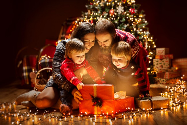 familie adunata in jurul badului cu instalatie, tata, mama si copil deschid cadouri