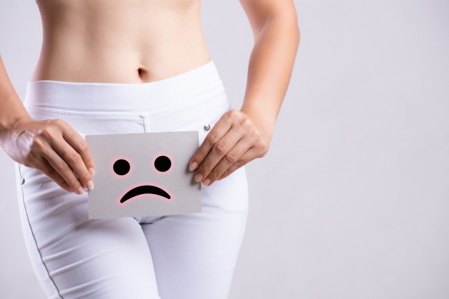 femeie in blugi albi cu probleme vaginale emoticon ce afiseaza tristete pe hartie