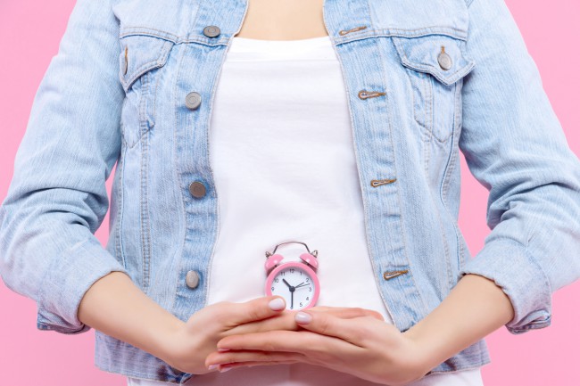 femeie imbracata in geaca de blugi cu ceas in dreptul abdomenului, intarziere ciclu menstrual