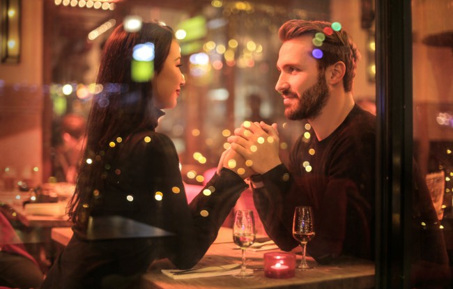 cuplu tanar si frumos vazut pe gem care bea sampanie si se priveste in ochi romantic la un restaurant