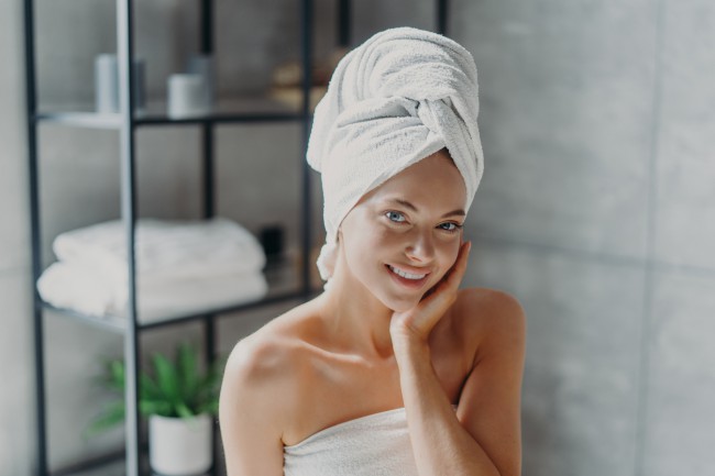 femeie dupa baie cu capul infasurat in prosop, femeie cu ten tanar si frumos, masaj facial dupa baie