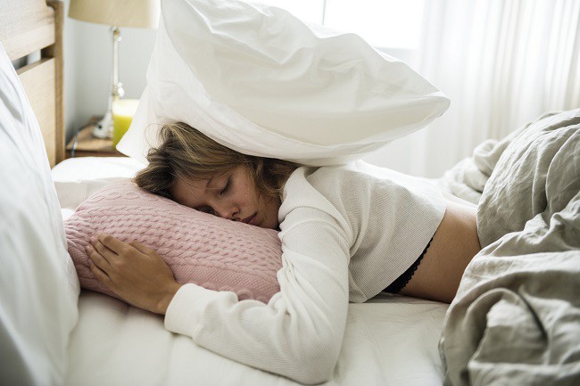 femeie care doarme cu perna in cap, femeie obosita in pat