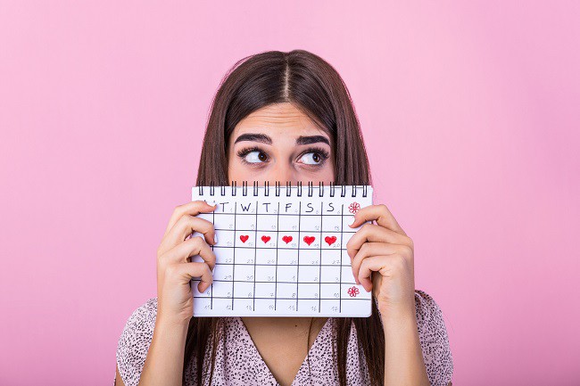 femeie ingrijorata care tine in mana calendarul menstrual