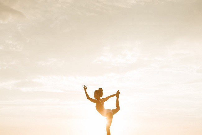 balerina care face sport in costum de baie cu soare la asfintit pe fundal