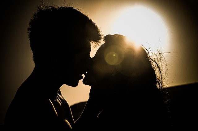 cuplu care se saruta cu lumina soarelui in fundal