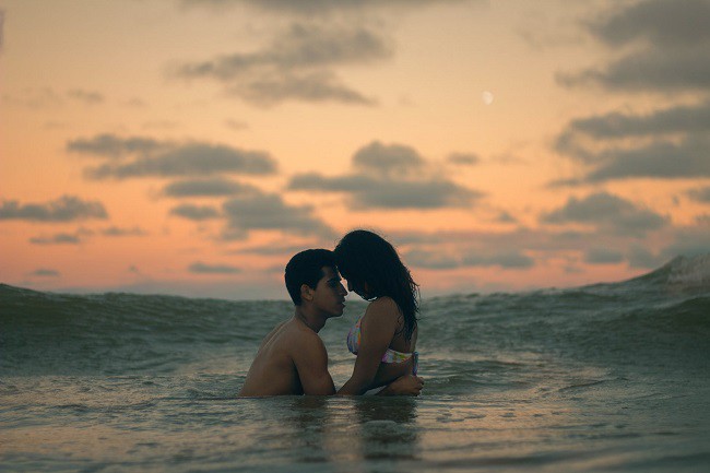 cuplu care se saruta in valurile marii