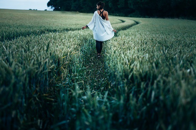 femeie imbracata in camasa care se plimba printr-un lan