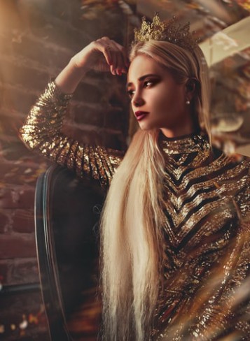femeie blonda si frumoasa imbracata in rochie cu paiete aurii si cu coroana de aur pe cap