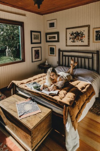 femeie care sta in casa si citeste o carte pe pat