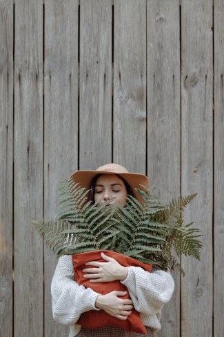 fata frumoasa cu palarie in cap care are in mana o planta verde