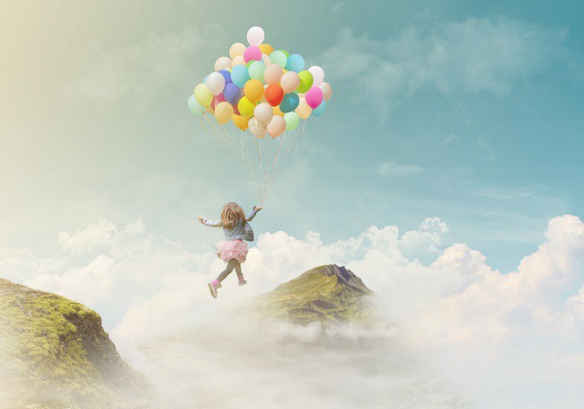 copil care zboara intre doua stanci cu baloane colorate