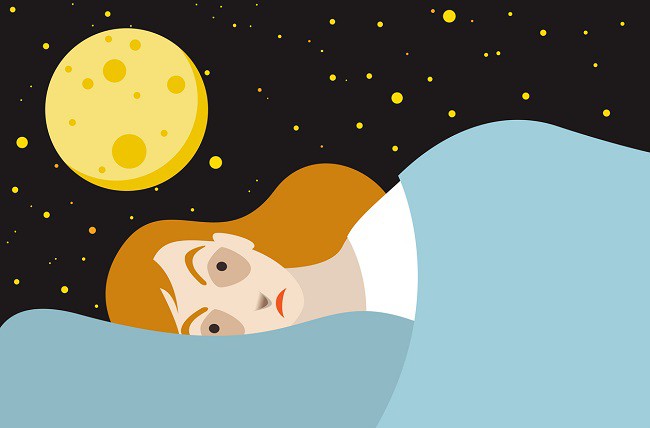 femeie preocupata intinsa in pat cu ochii deschisi si cu luna pe fudal