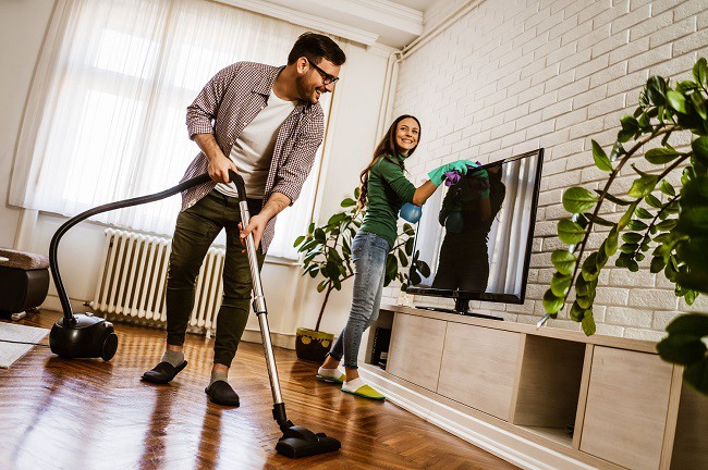 femeie si barbat care fac curatenie intr-o casa cu multe plante