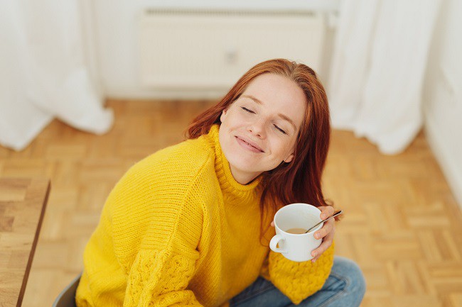 femeie frumoasa intr-un pulover galben care bea ceai dintr-o ceasca