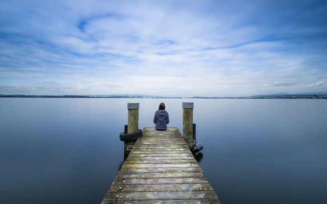 femeie care se bucura de natura pe un ponton la marginea unui lac
