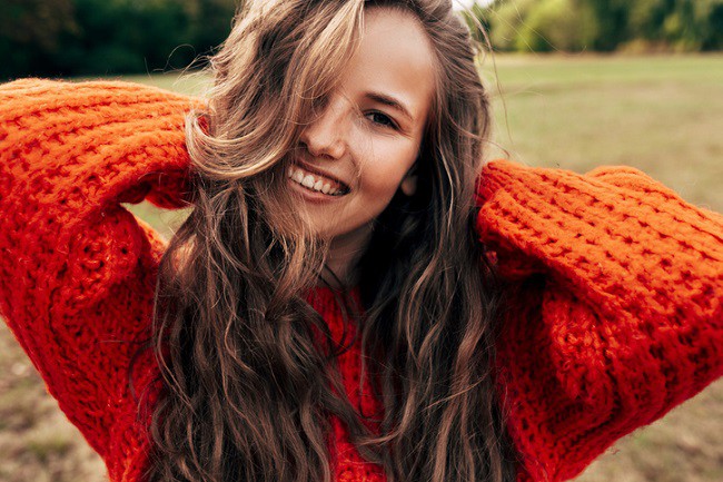 femeie fericita in pulover portocaliu