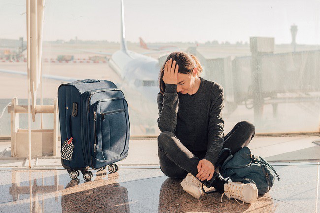 femeie trista din cauza zborului anulat care sta aluturi de bagajul sau