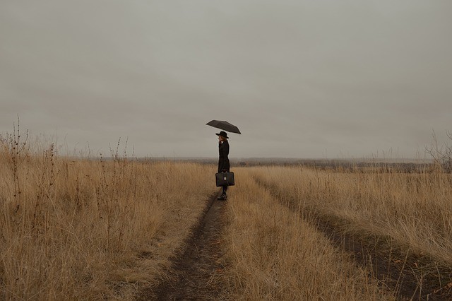 femeie care sta singura intr-un camp cu o umbrela