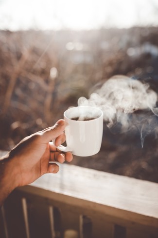 femeie care bea o ceasca de cafea neagra pe un balcon la munt