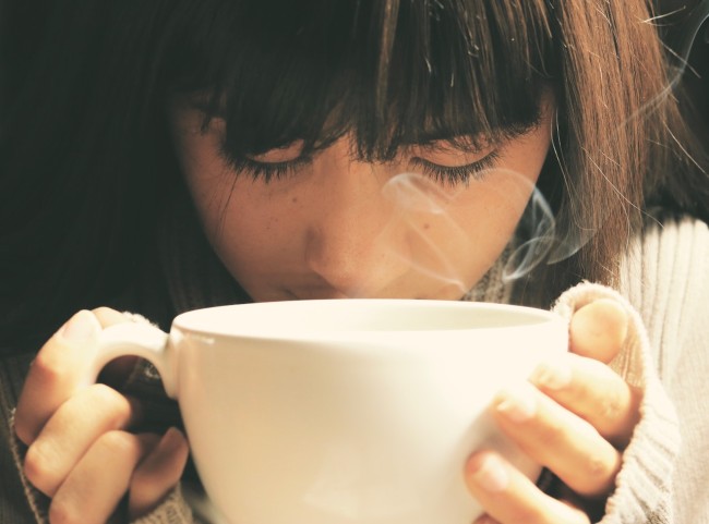 fata imbracata in pulover care bea o cana de ceai