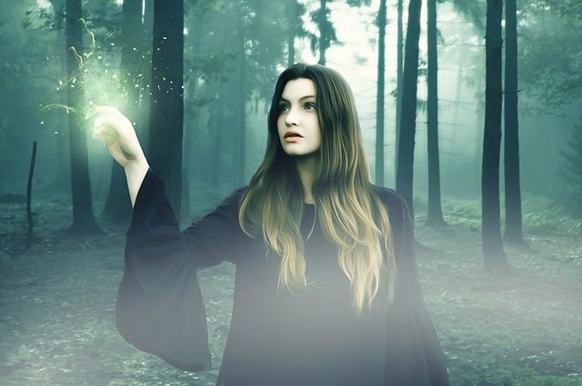 vrajitoare tanara intr-o padure care face o vraja de lumina