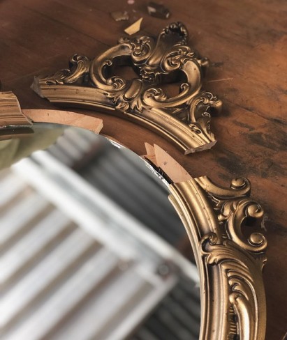 oglinda veche cu rama aurita pe o suprafata de lemn