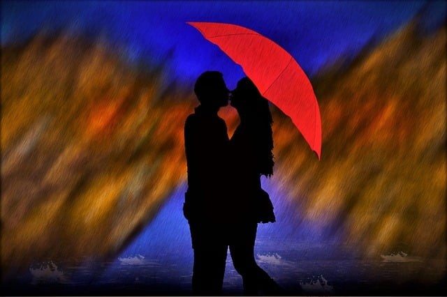 cuplu care se saruta pe un fundal colorat care tine o umbrela rosie in mana