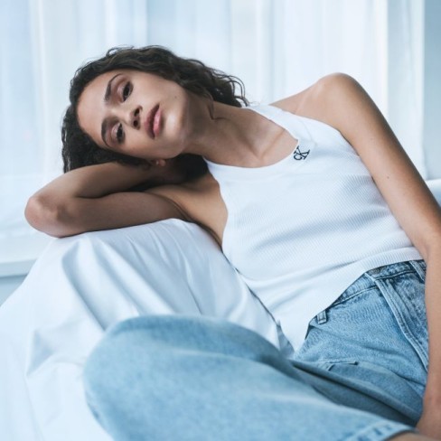 model calvin klein imbracat in maiou alb si in blugi