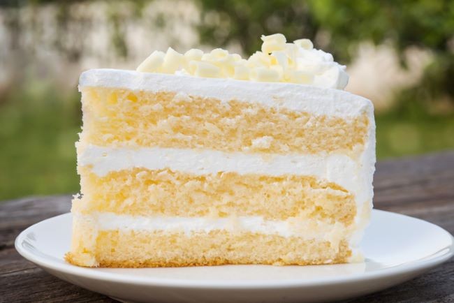felie de tort asezata pe farfurie si umplut cu crema alba