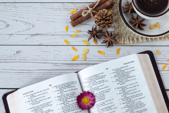 imagine cu biblia pe un blat de lemn alaturi de o ceasca de cafea si condiment