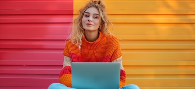 femeie blonda imbracata in portocaliu care are un laptop in brate