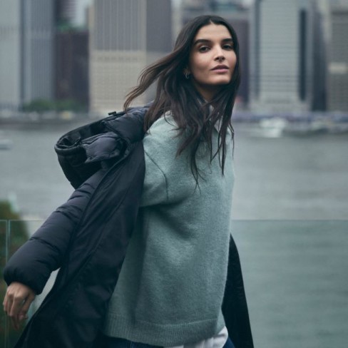 model calvin klein imbracat in pulover gros cu geaca puffer si jeans