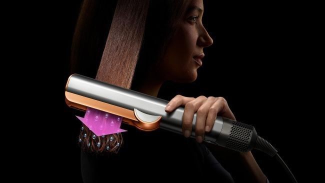 imagine cu placa de par Dyson Airstrait™ de culoare portocalie pe parul drept si stralucitor al unei femei in profil