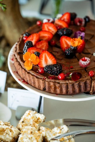 imagine cu un tort de ciocolata aflat pe stativ si decorat cu fructe de padure