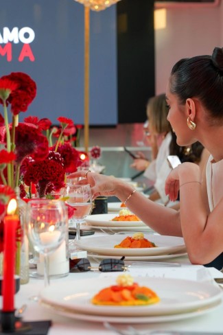 imagine de la un eveniment cu decoruri in tonuri de rosu la care diverse persoane stau la masa