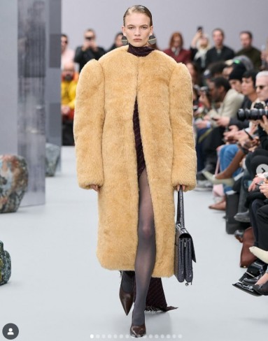 model de pe catwalk care poarta haina de blana oversized