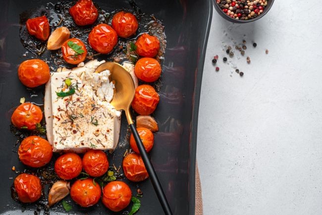 imagine cu rosii la cuptor alaturi de branza feta si condimente