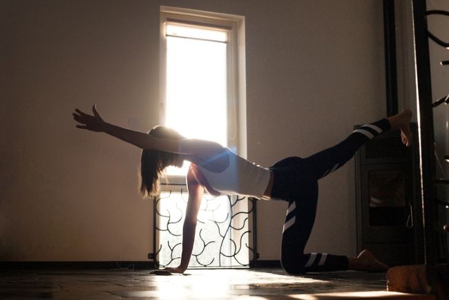 femeie care sta in patru labe si face exercitii in fata geamului