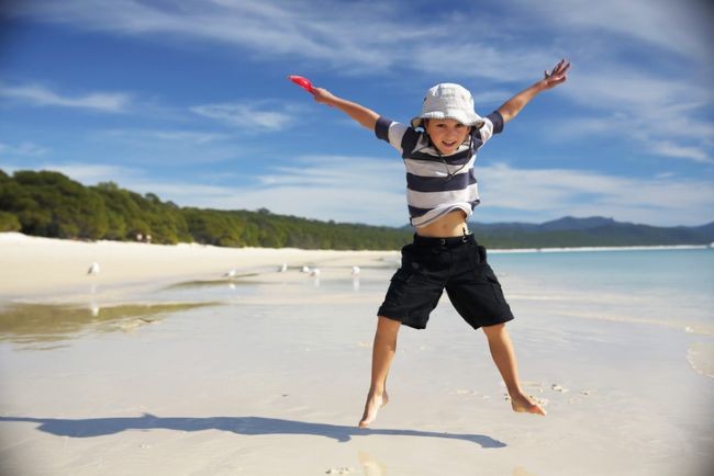 baietel care sare in sariturile jumping jacks pe malul unei ape