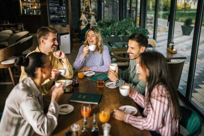 imagine cu mai multi prieteni asezati la masa la o cafea