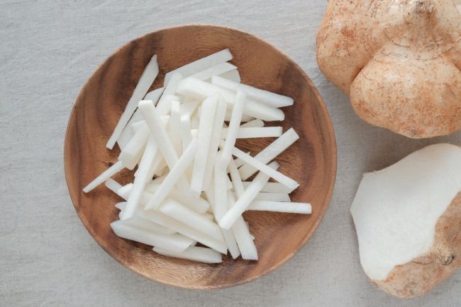 feliute de jicama albe si proaspete intr-un castron alaturi de detaliu leguma taiata