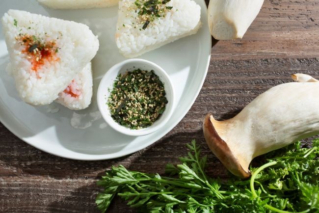 bol cu furikake alaturi de triunghiuri de orz si verdeturi in coltul imaginii
